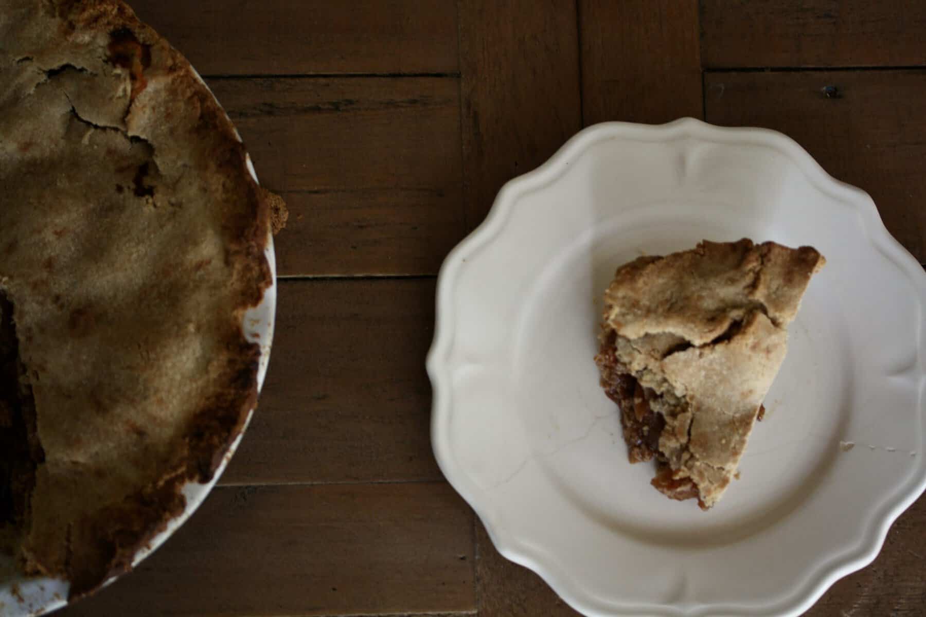 Delicious Gravenstein Apple Pie makes the most of the apple's short season. Make this pie when Gravs are in season - you won't regret it! A piece of apple pie on a plate next to an apple pie.