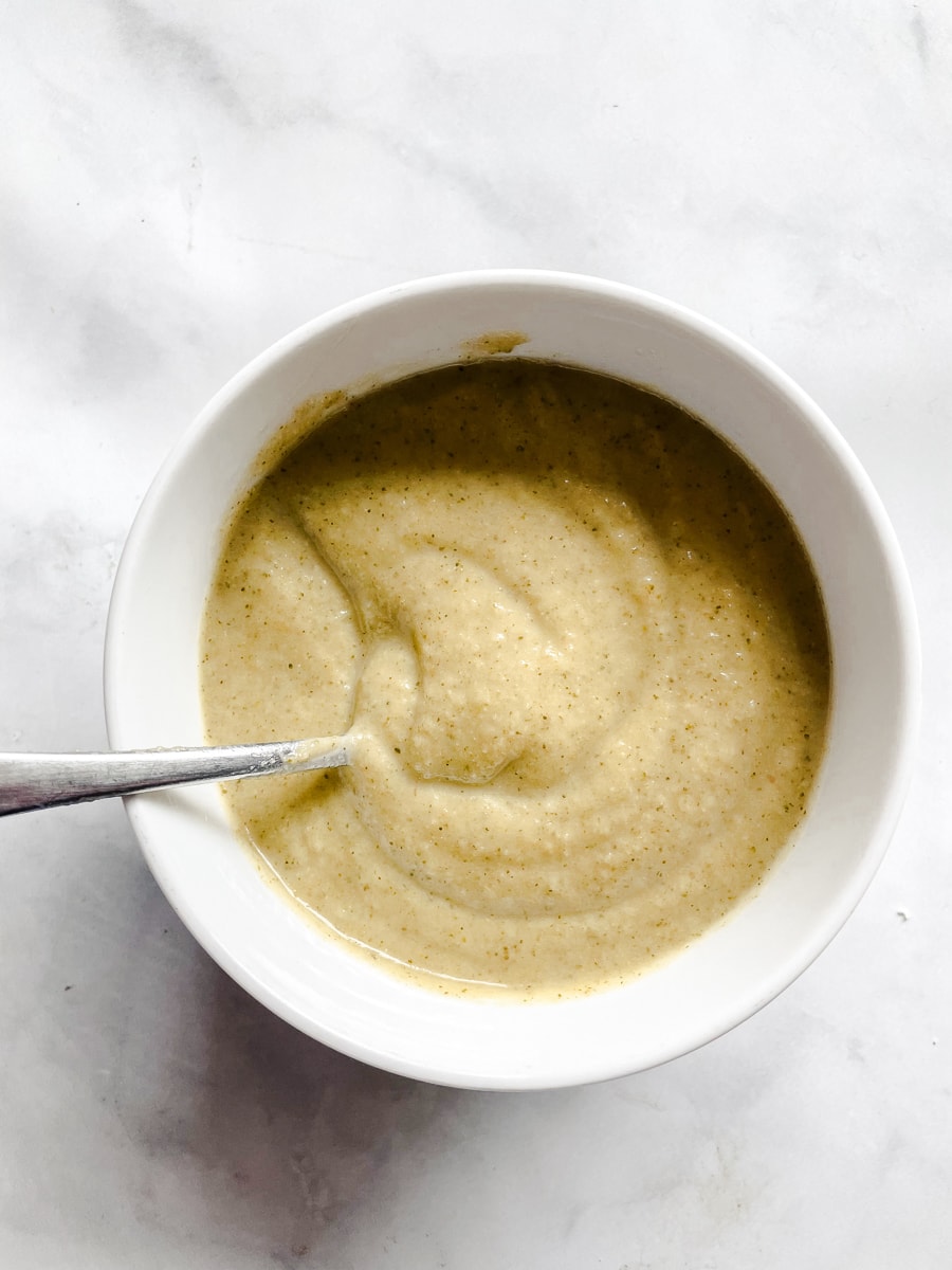 A bowl of broccoli soup with a spoon in it.