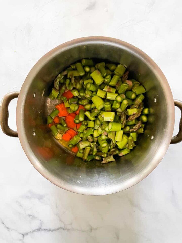 Creamy vegan asparagus soup that's full of fresh vegetable flavors and vibrantly green from plenty of asparagus. Asparagus is added to the pot.
