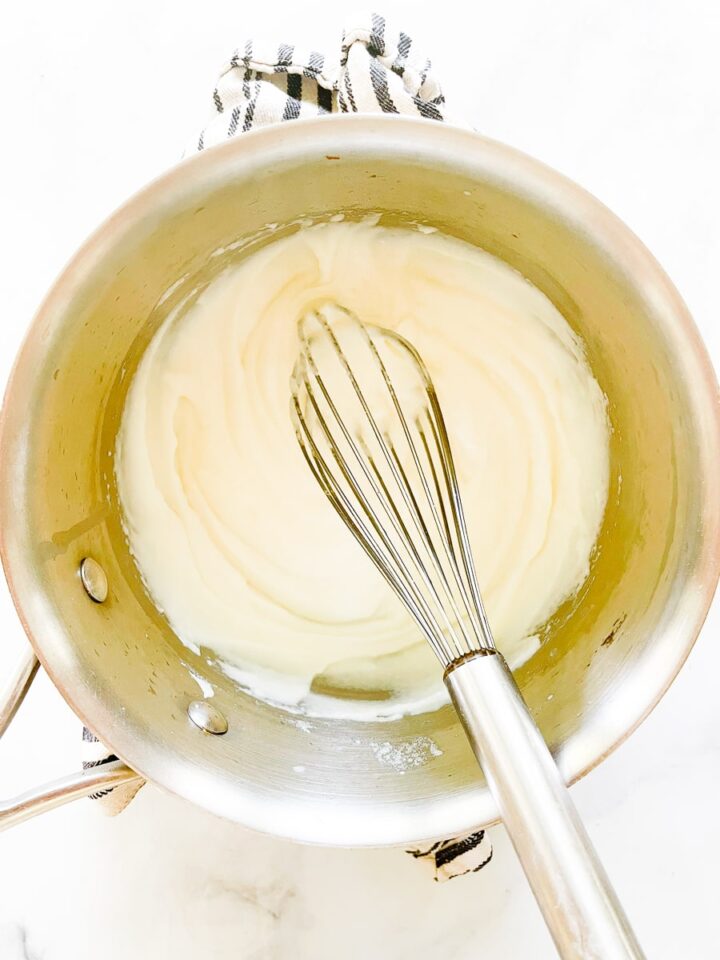 The fluffiest gluten free souffle with spinach and parmesan cheese is easily made gluten-free by using sweet white rice flour. The roux is whisked in a pot.