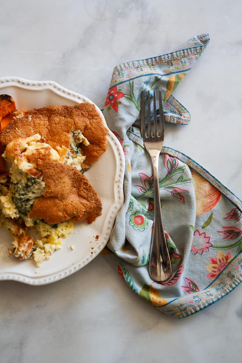 A blue napkin with a fork to the right of a plate of gluten free souffle.