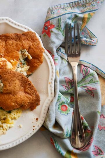 A blue napkin with a fork to the right of a plate of gluten free souffle.