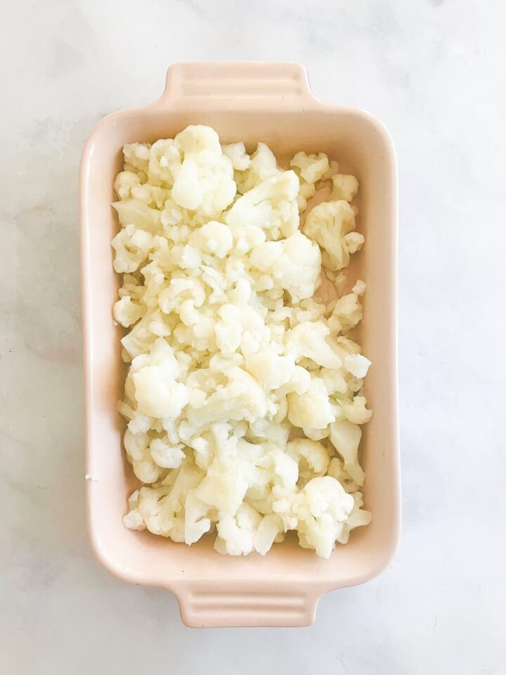Salty and rich, this cauliflower cheese casserole makes enough for a hearty vegetarian main dish along with a fresh salad. Cauliflower is placed in the baking dish.