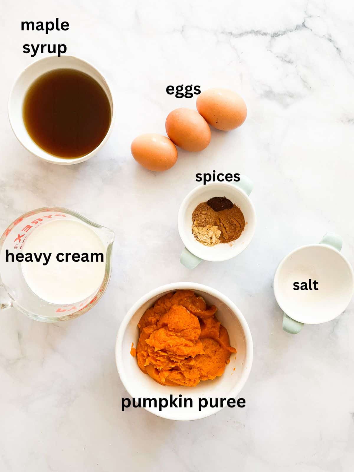 A gorgeous and easy homemade pumpkin pie made with heavy cream rather than condensed milk and sweetened with pure maple syrup! Ingredients for homemade pumpkin pie including eggs and maple syrup are text-labeled.