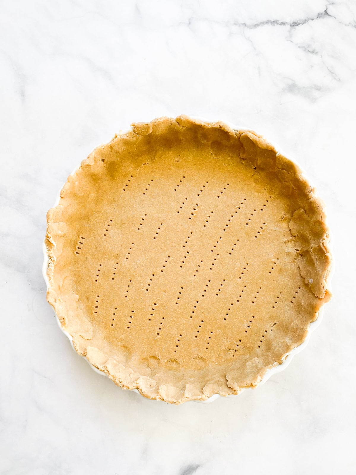 A gorgeous and easy homemade pumpkin pie made with heavy cream rather than condensed milk and sweetened with pure maple syrup! A crust is pricked all over with a fork.