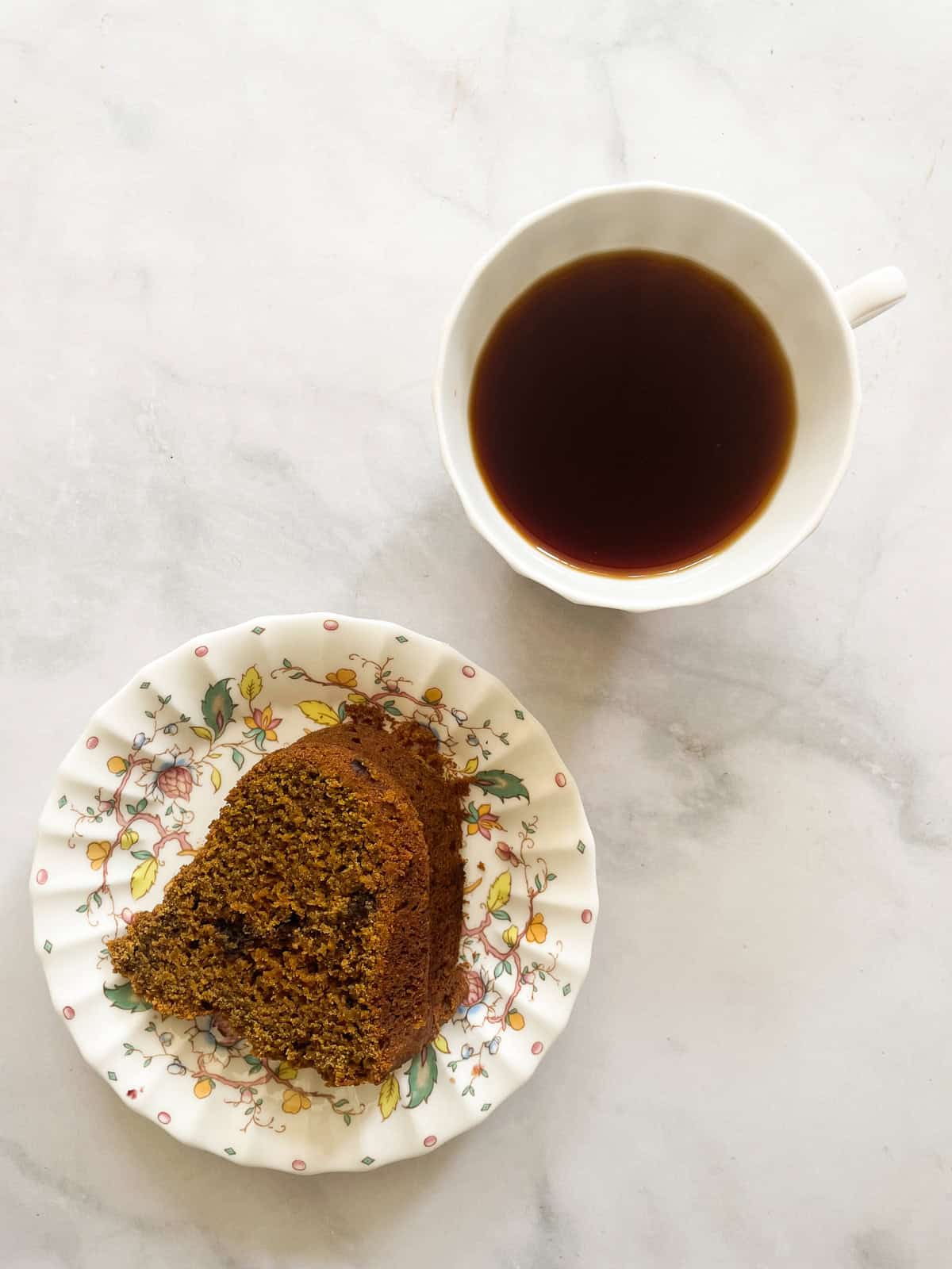 This tender pumpkin spice cake recipe takes a fluffy pumpkin cake and swirls it with a cozy chocolate-spiked cinnamon streusel. A piece of pumpkin spice cake on a plate with a cup of tea.