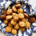 A bowl lined with a napkin full of banana mini muffins.