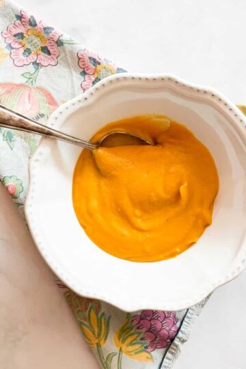 A spoon rests in a bowl of butternut squash soup.