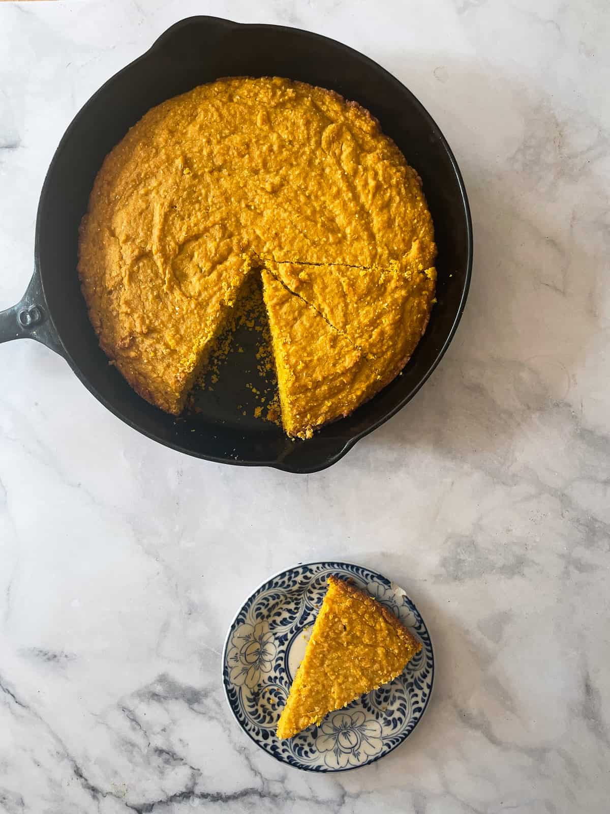 Savory-sweet ultra moist gluten free pumpkin cornbread is a fun and festive holiday side you'll love with soup, stew, and more! A pan of pumpkin cornbread and a slice of cornbread on a plate.
