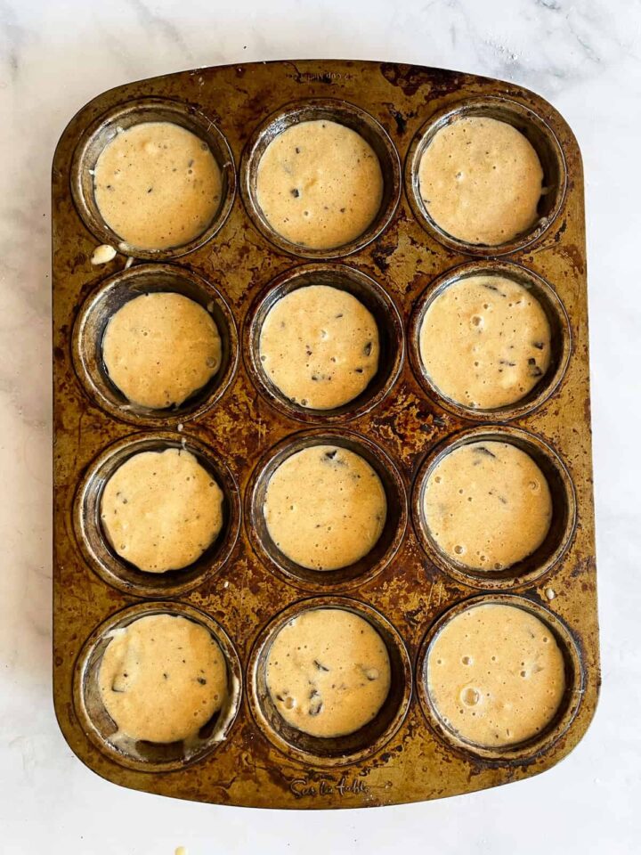 Sweet and moist banana chocolate chunk muffins are studded with big bites of semisweet chocolate for a decadent morning treat. Banana chocolate chunk muffins batter in a tin.