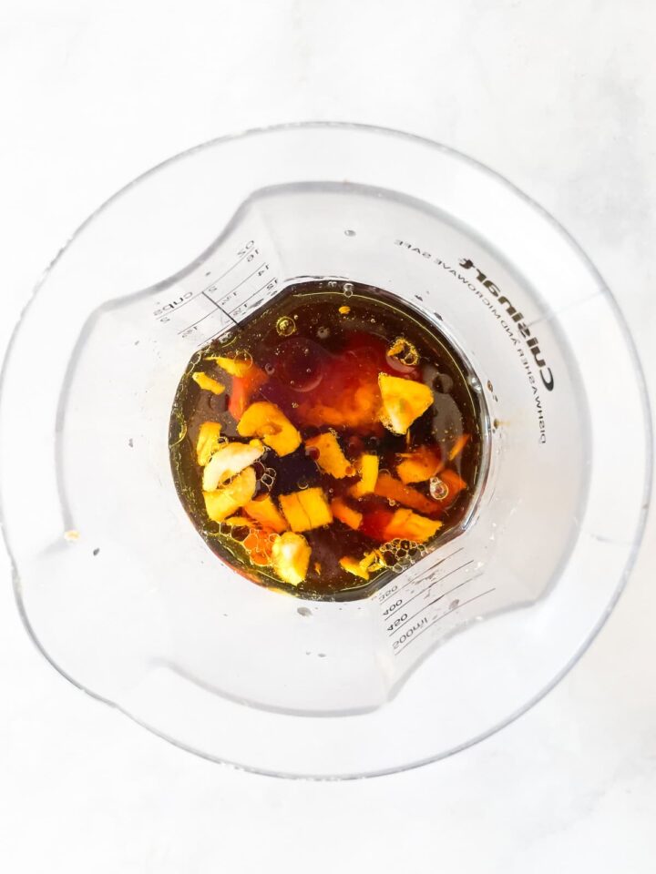 Silky smooth ginger peanut sauce features fresh ginger swirled with lots of peanut butter, a little garlic, tamari sauce, and sesame sauce. Ginger peanut sauce ingredients added to a blender.