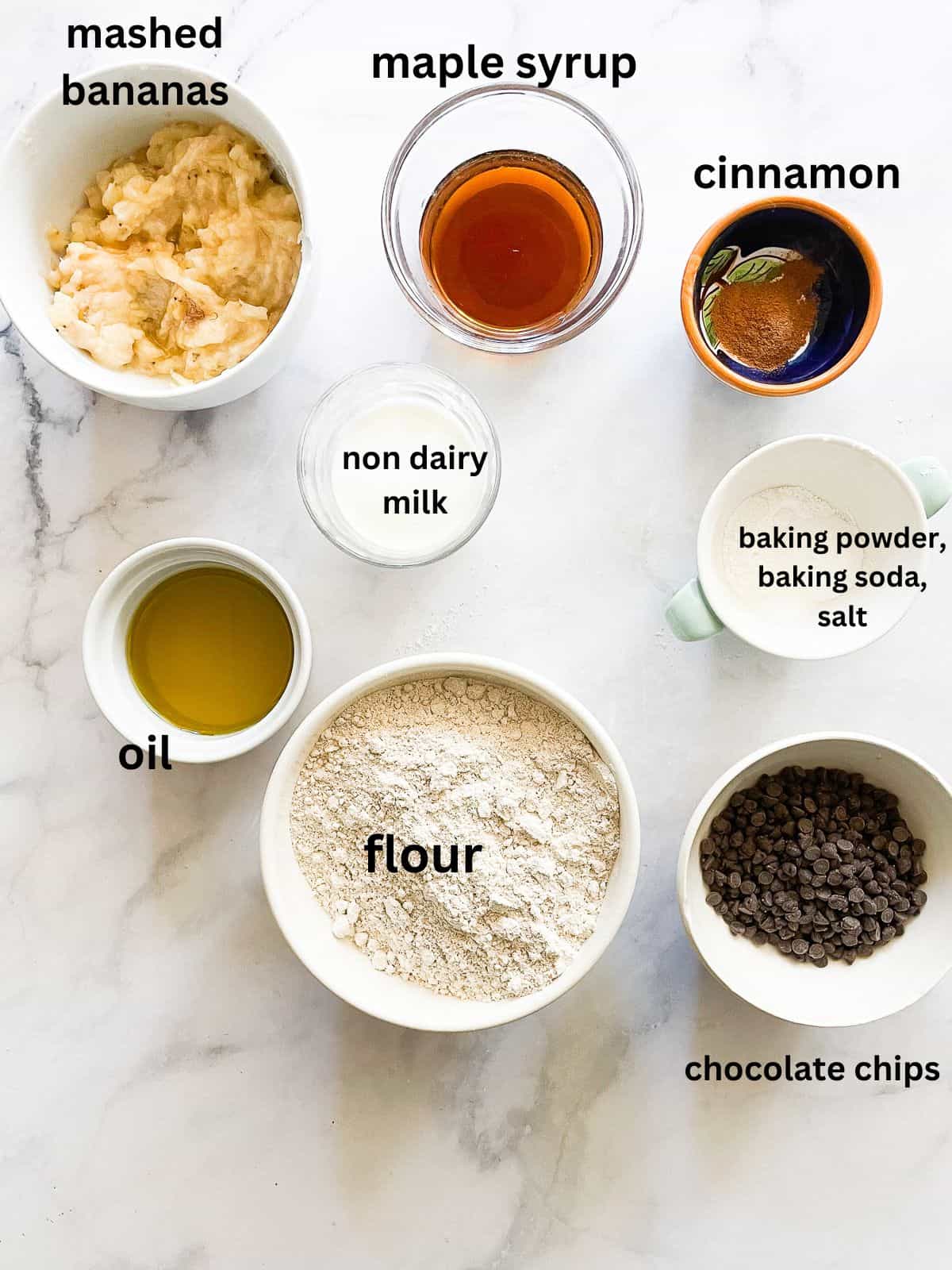 These easy vegan banana muffins are soft, sweet, and easily made gluten-free. Maple syrup and ripe banana stand out. Ingredients for vegan banana muffins are portioned and text-labeled.