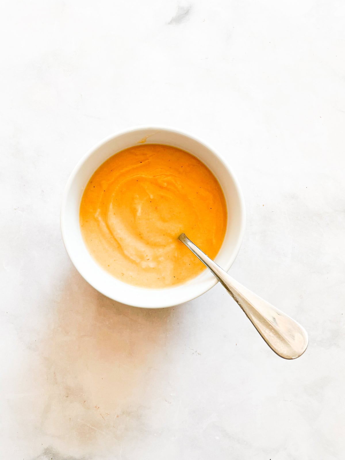 This creamy carrot cauliflower soup is packed with garlic, lots of carrots, and a whole cauliflower. Hearty enough for dinner! A bowl of carrot cauliflower soup with a spoon.