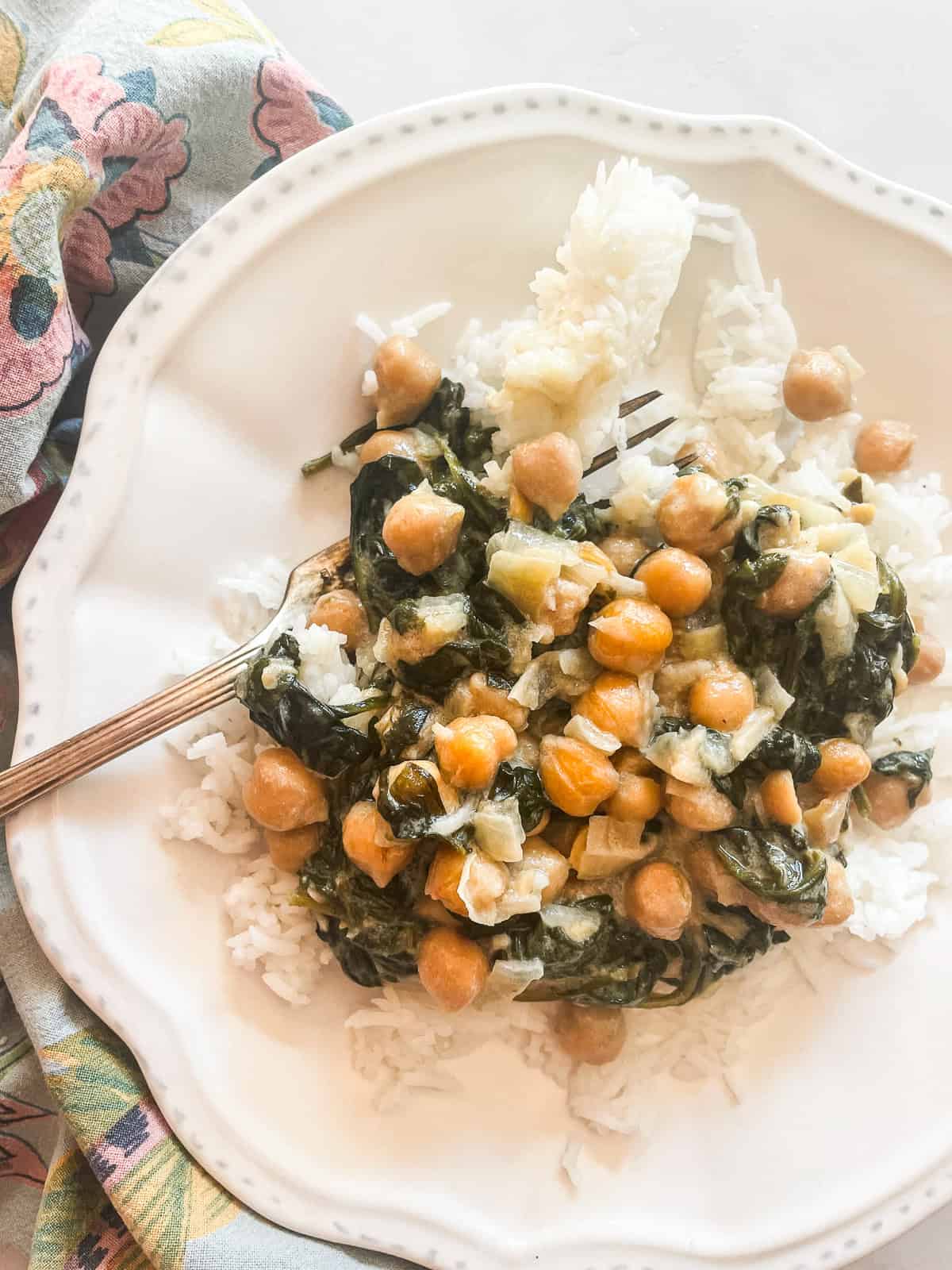 Easy curried chickpeas with coconut and spinach are spiked with fresh lemon juice. Serve over brown rice or quinoa for a gluten-free dinner. A plate of curried chickpeas with coconut milk.