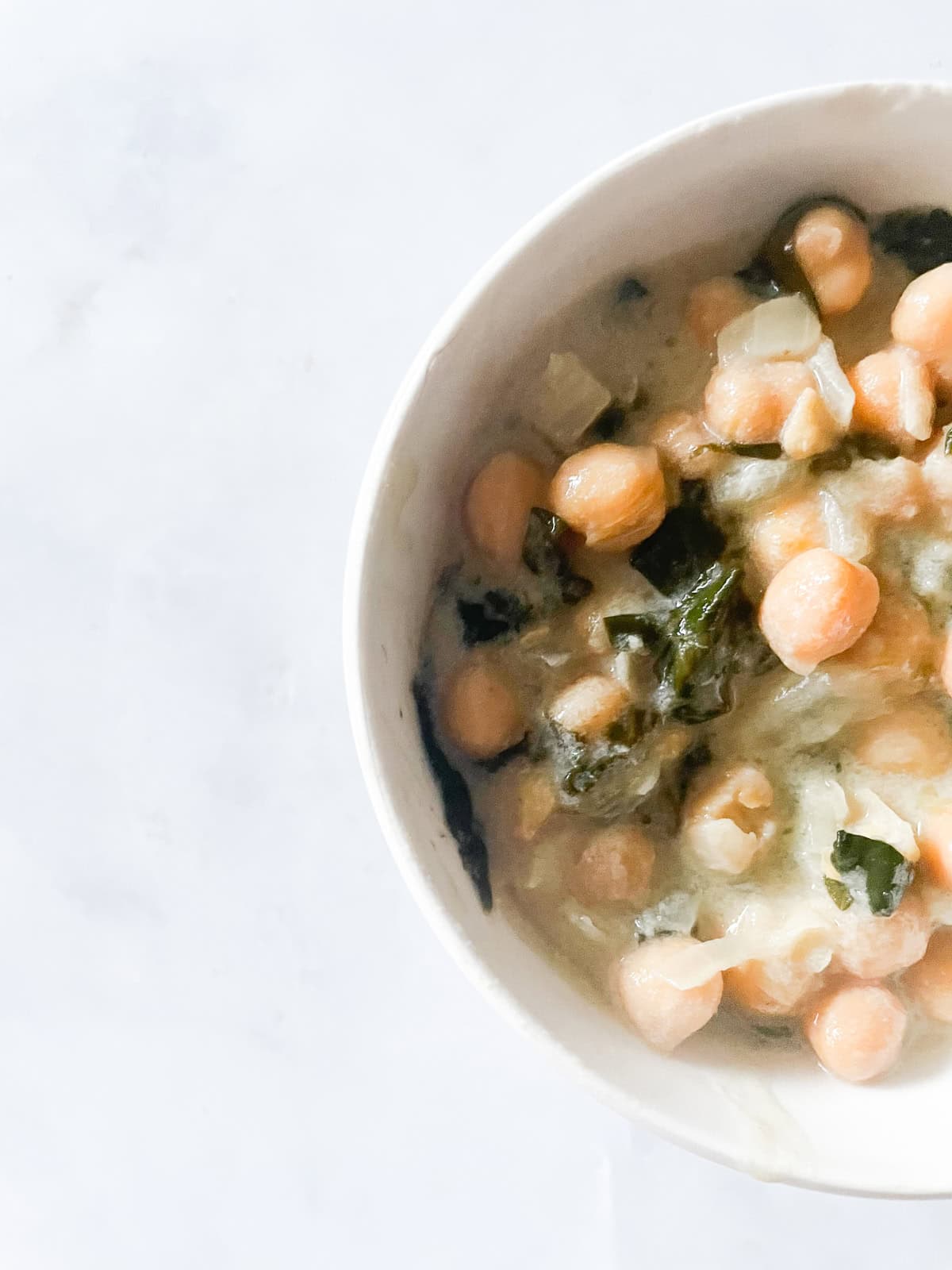 Easy curried chickpeas with coconut and spinach are spiked with fresh lemon juice. Serve over brown rice or quinoa for a gluten-free dinner. A bowl of coconut milk chickpeas and spinach.