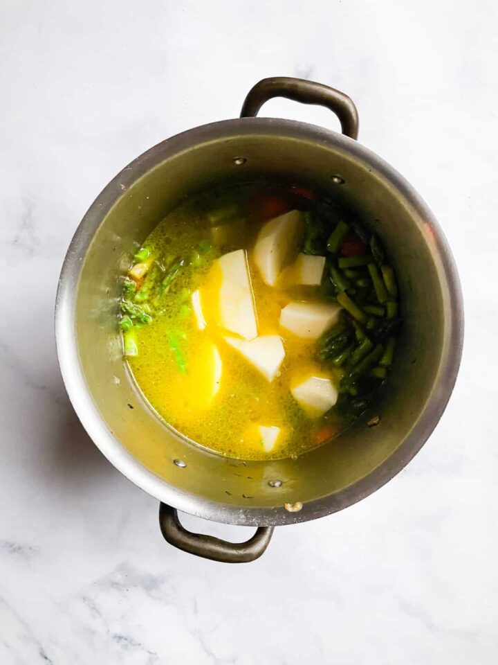 Creamy, cozy asparagus potato soup is crammed with vibrant vegetables like carrots, spinach, and potatoes. Pretty and satisfying! Water and potatoes added to a soup pot.