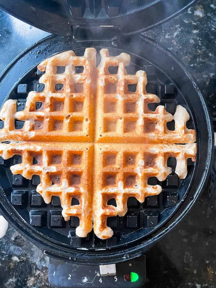 Fluffy whole wheat waffles made with whole grain flour, Greek yogurt, and melted butter! Perfect for a lazy weekend morning. A waffle cooks on a waffle iron.