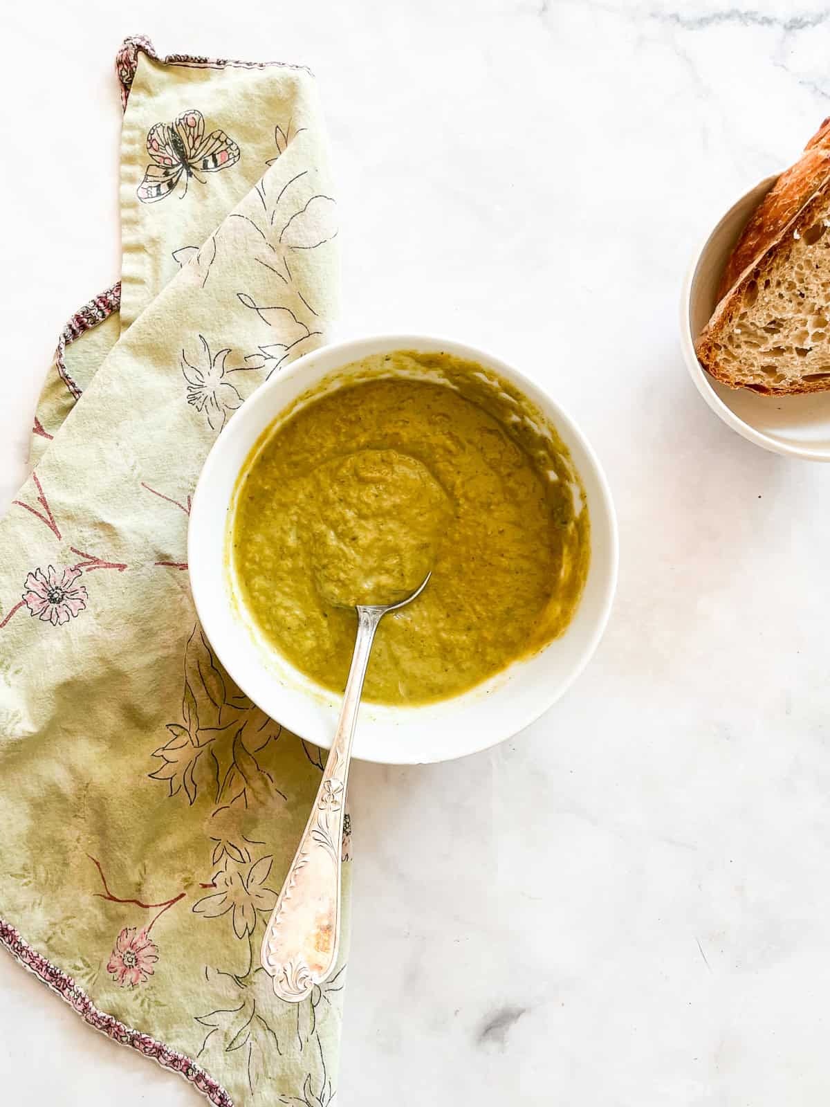 A bowl of asparagus potato soup with a spoon in it.
