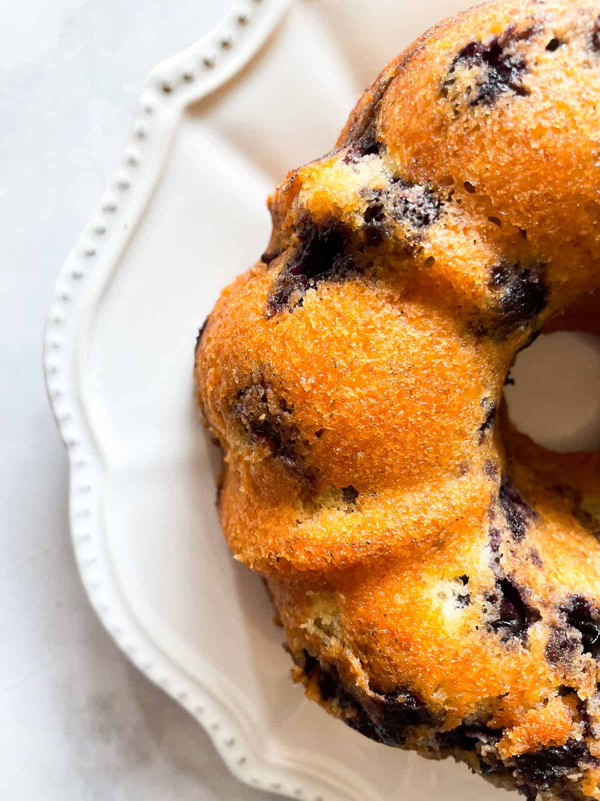 Half of a blueberry yogurt cake on a plate.