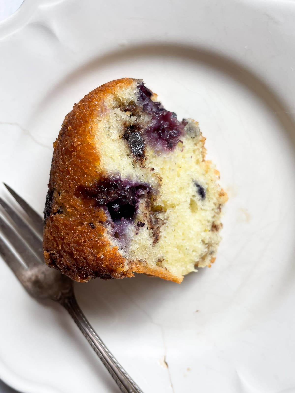 This luscious blueberry yogurt cake is loaded with juicy berries and a sweet cinnamon swirl. Gluten-free option included! Blueberries are seen in a plate of blueberry yogurt cake with a fork.