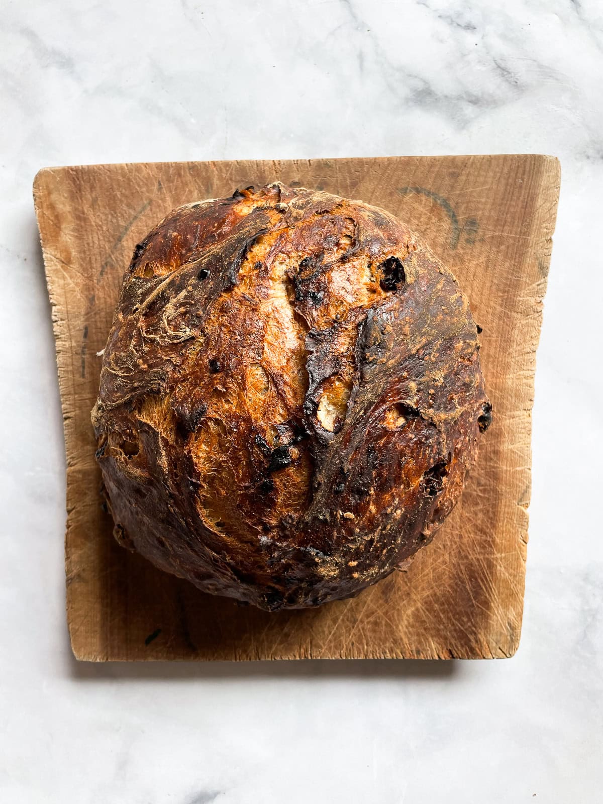 A loaf of cinnamon raisin bread on a wooden cutting board.