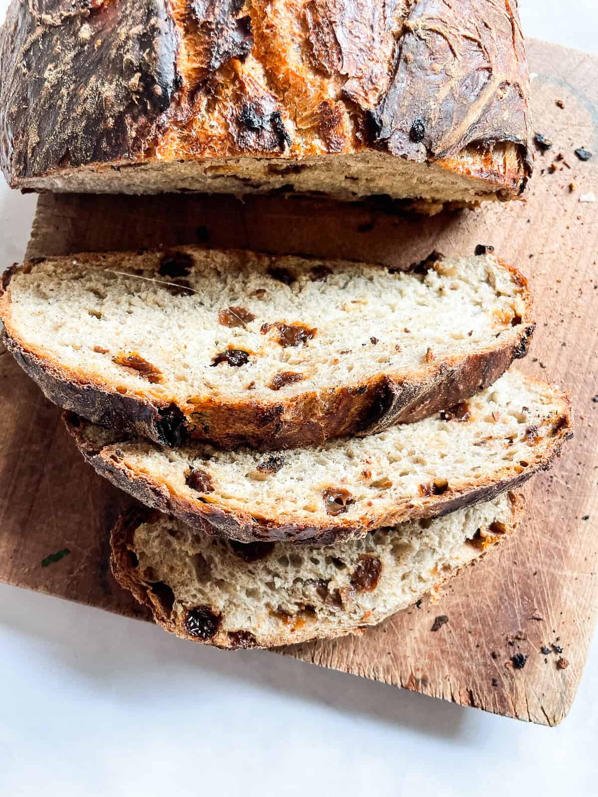 Easy no knead cinnamon raisin bread benefits from a long overnight rise and a bake in a hot Dutch oven! A fantastic recipe for beginners. A loaf of cinnamon raisin bread on a wooden cutting board cut into slices.