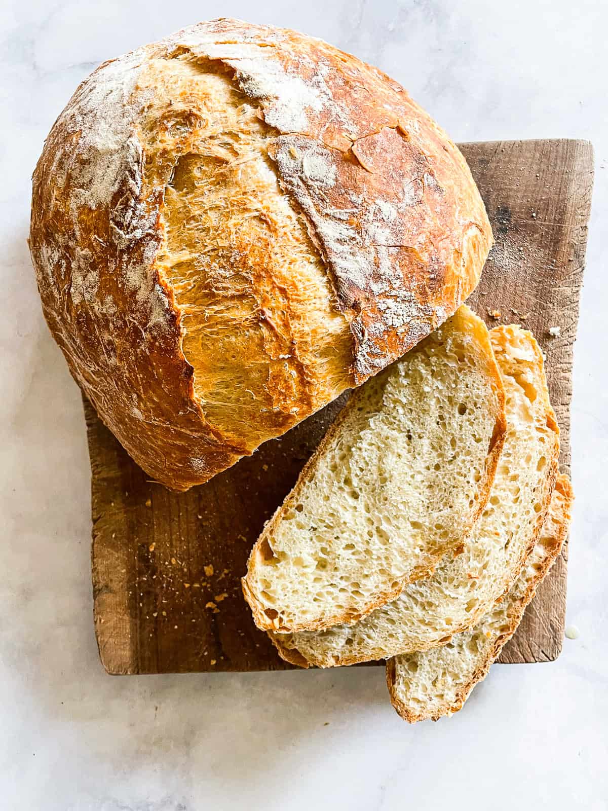 A loaf of easy dutch oven bread on a cutting board cut into slices.