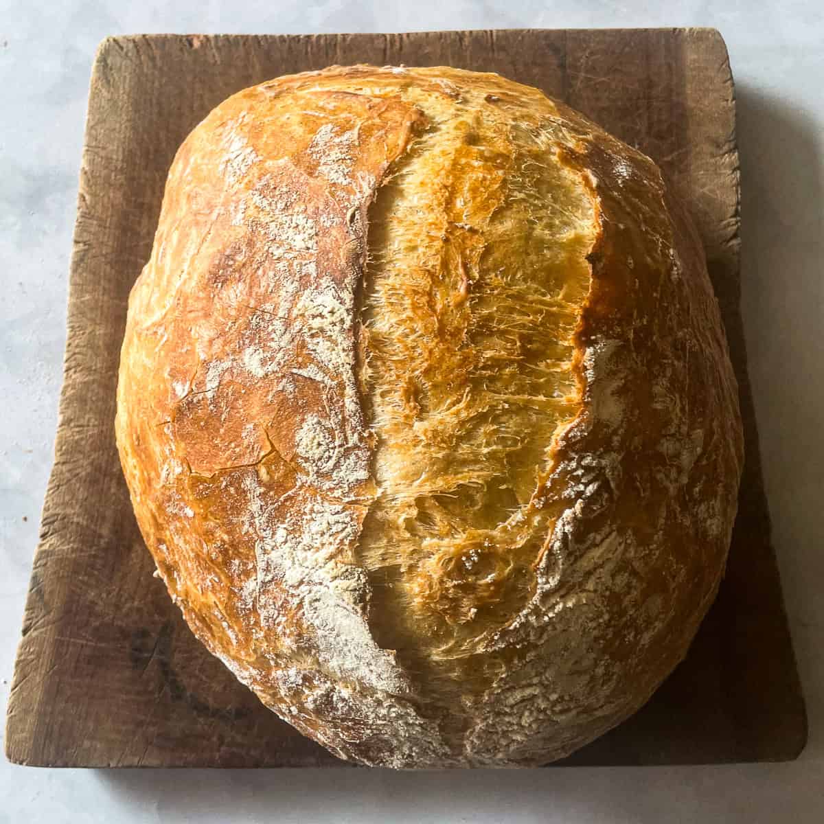 A loaf of easy dutch oven bread on a wooden cutting board.