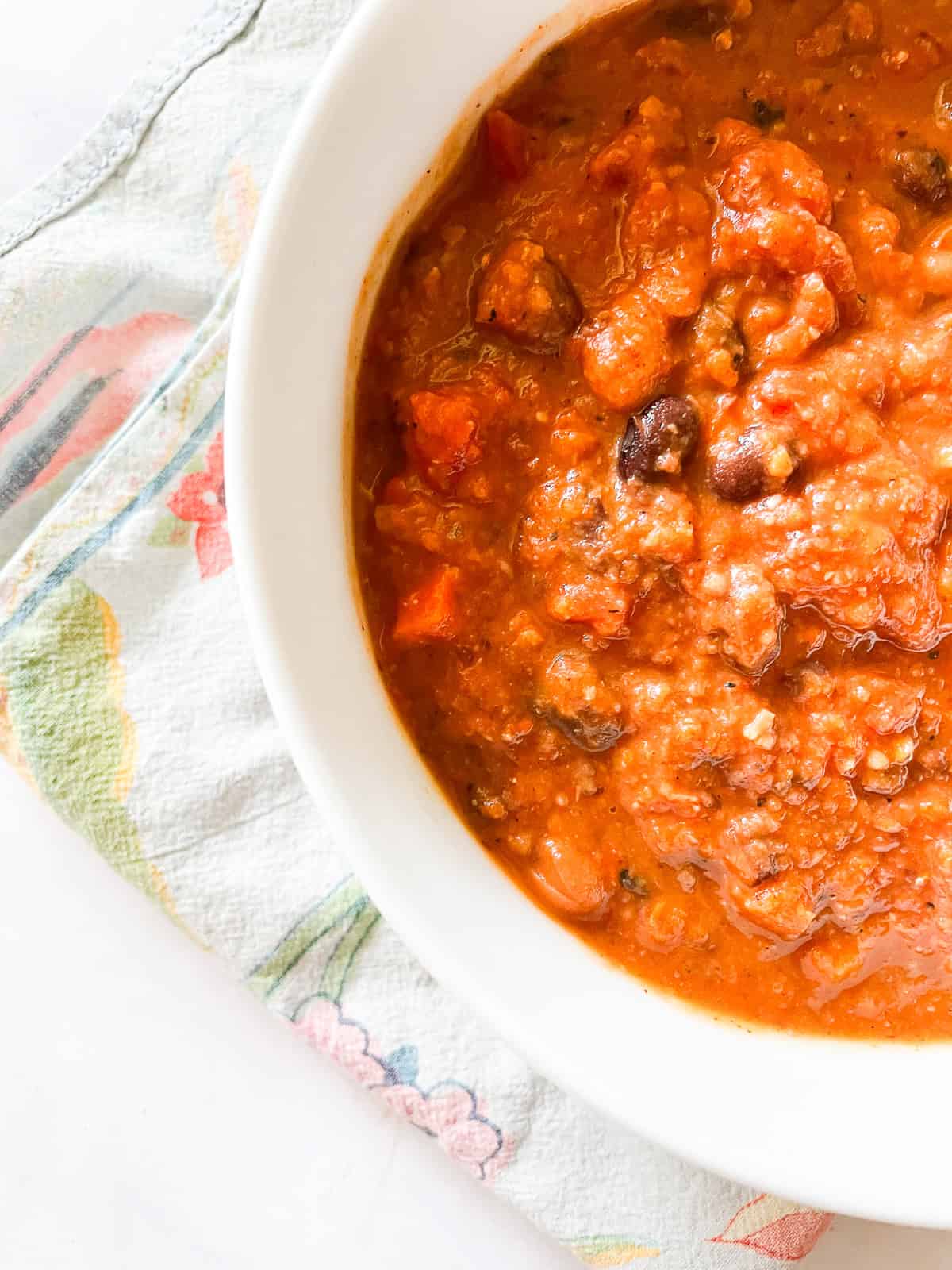 Gluten free chili is packed with two kinds of beans, smoky spices, crushed tomatoes, and other veggies. Also vegetarian! Half a a bowl of gluten free chili on a napkin.