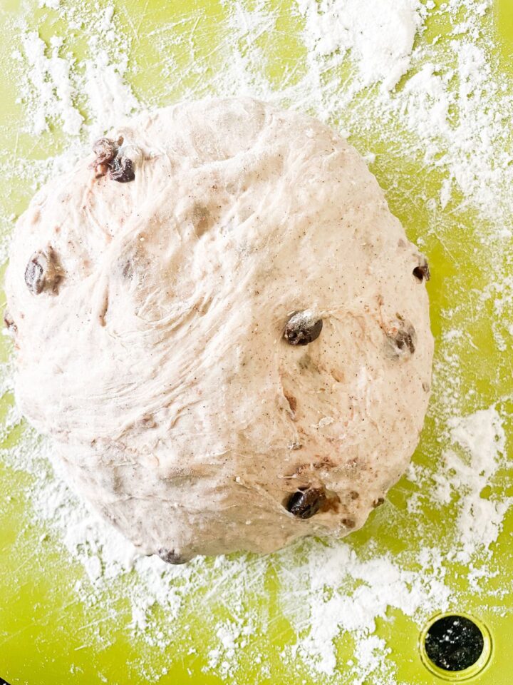 Easy no knead cinnamon raisin bread benefits from a long overnight rise and a bake in a hot Dutch oven! A fantastic recipe for beginners. A loaf of risen cinnamon raisin bread dough on a cutting board.