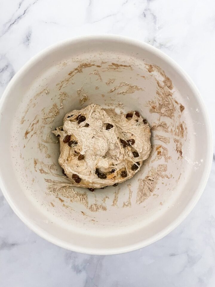 Easy no knead cinnamon raisin bread benefits from a long overnight rise and a bake in a hot Dutch oven! A fantastic recipe for beginners. Cinnamon raisin bread dough in a bowl.