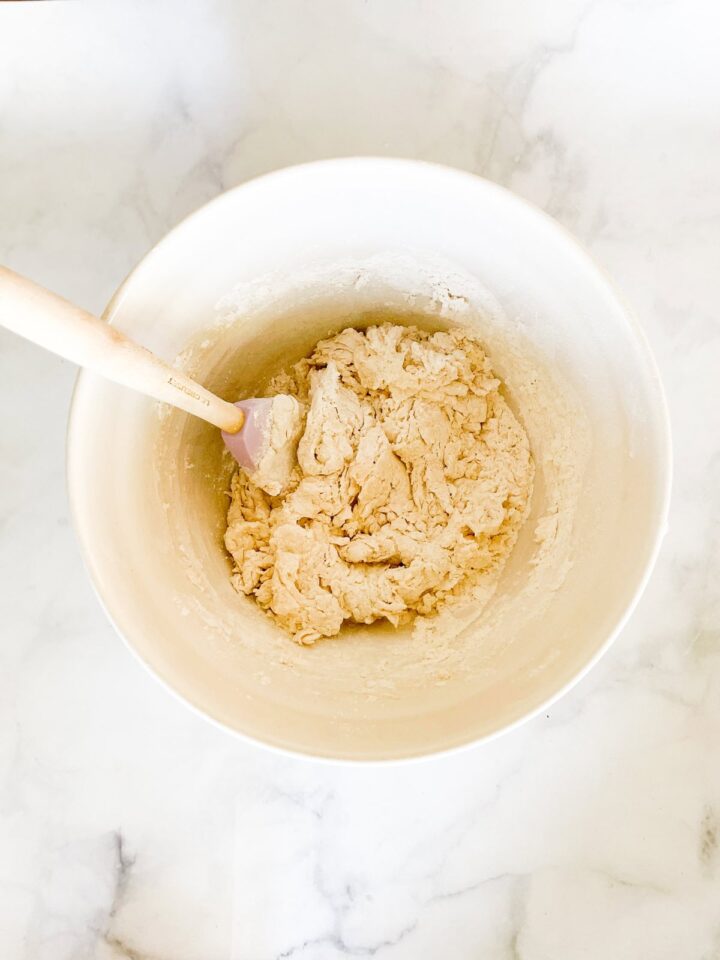 This easy no knead whole wheat bread is my version of the beloved no-knead bread recipe made with whole grain flour. A spatula stirs no knead bread dough in a bowl.