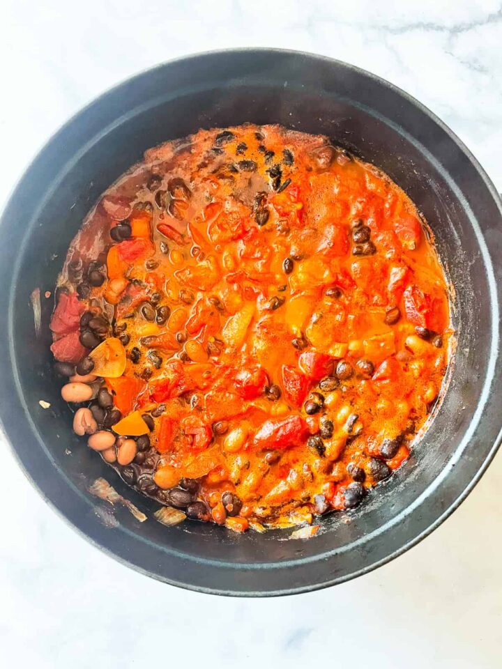 Gluten free chili is packed with two kinds of beans, smoky spices, crushed tomatoes, and other veggies. Also vegetarian! Tomatoes added to a pot of chili.