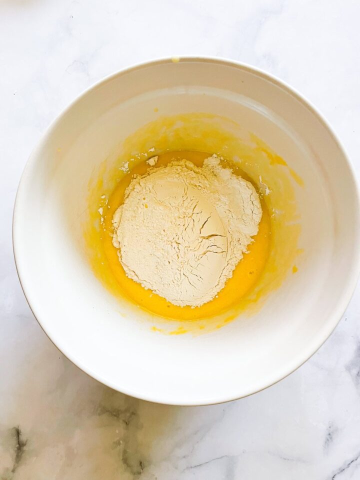 This classic French-inspired lemon yogurt cake is a reliable one-bowl recipe that always turns out perfectly. Flour is added to cake batter in a bowl.