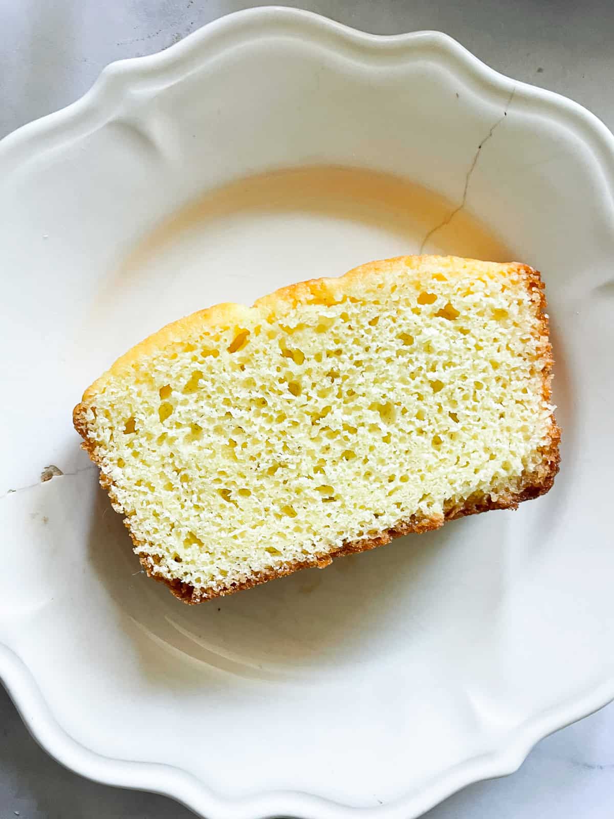 This classic French-inspired lemon yogurt cake is a reliable one-bowl recipe that always turns out perfectly. A slice of lemon yogurt cake on a plate.