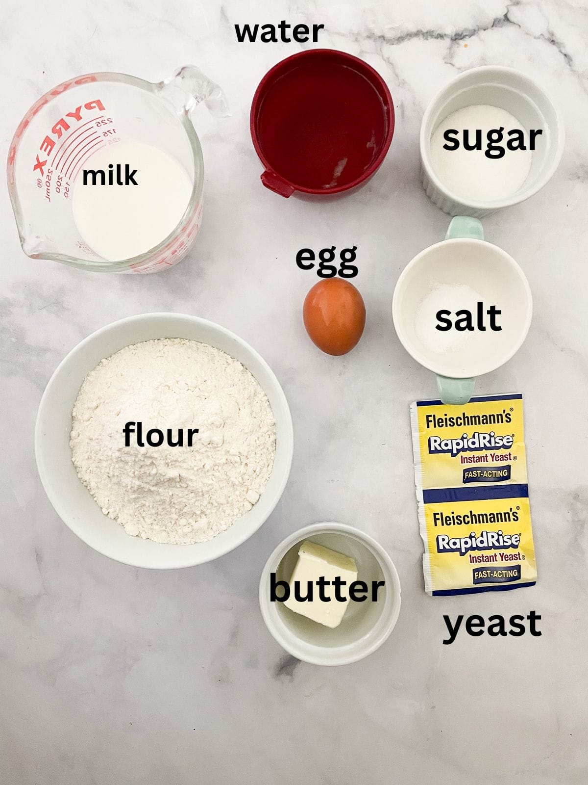 Kids love bunny bread that stars an easy, yeast-based dough that's simple to mix, fun to knead, and bakes up into the cutest golden bunnies. Ingredients for bunny bread are text-labeled.