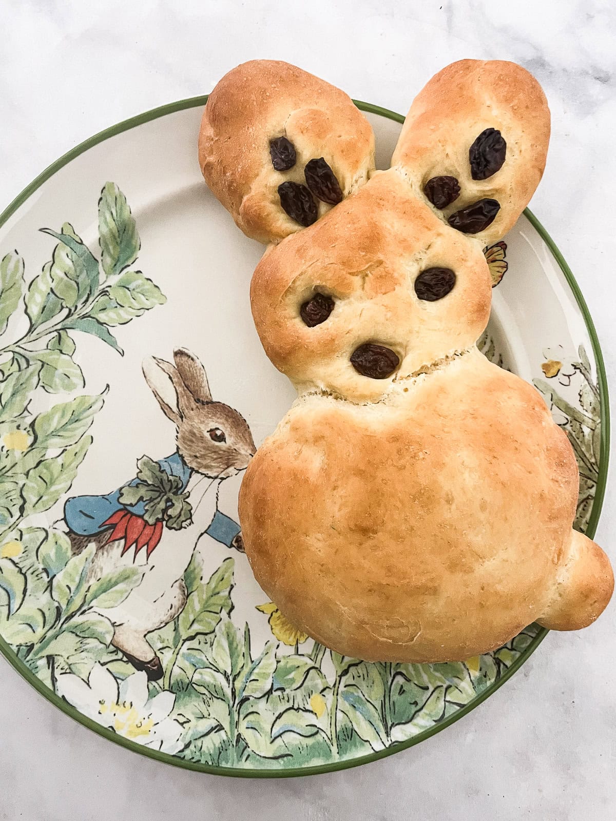 Kids love bunny bread that stars an easy, yeast-based dough that's simple to mix, fun to knead, and bakes up into the cutest golden bunnies. A bunny bread on a peter rabbit plate.