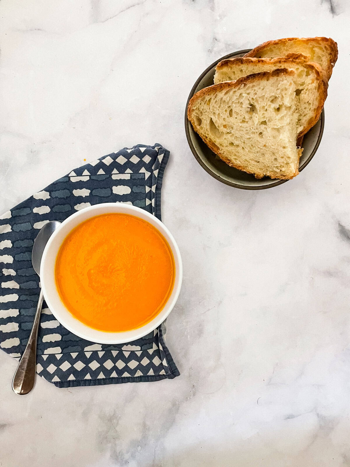 Creamy carrot & coconut soup made with simple ingredients. Naturally vegan, gluten-free, and perfect for weeknight dinners or meal prep. A bowl of carrot coconut soup and bread.