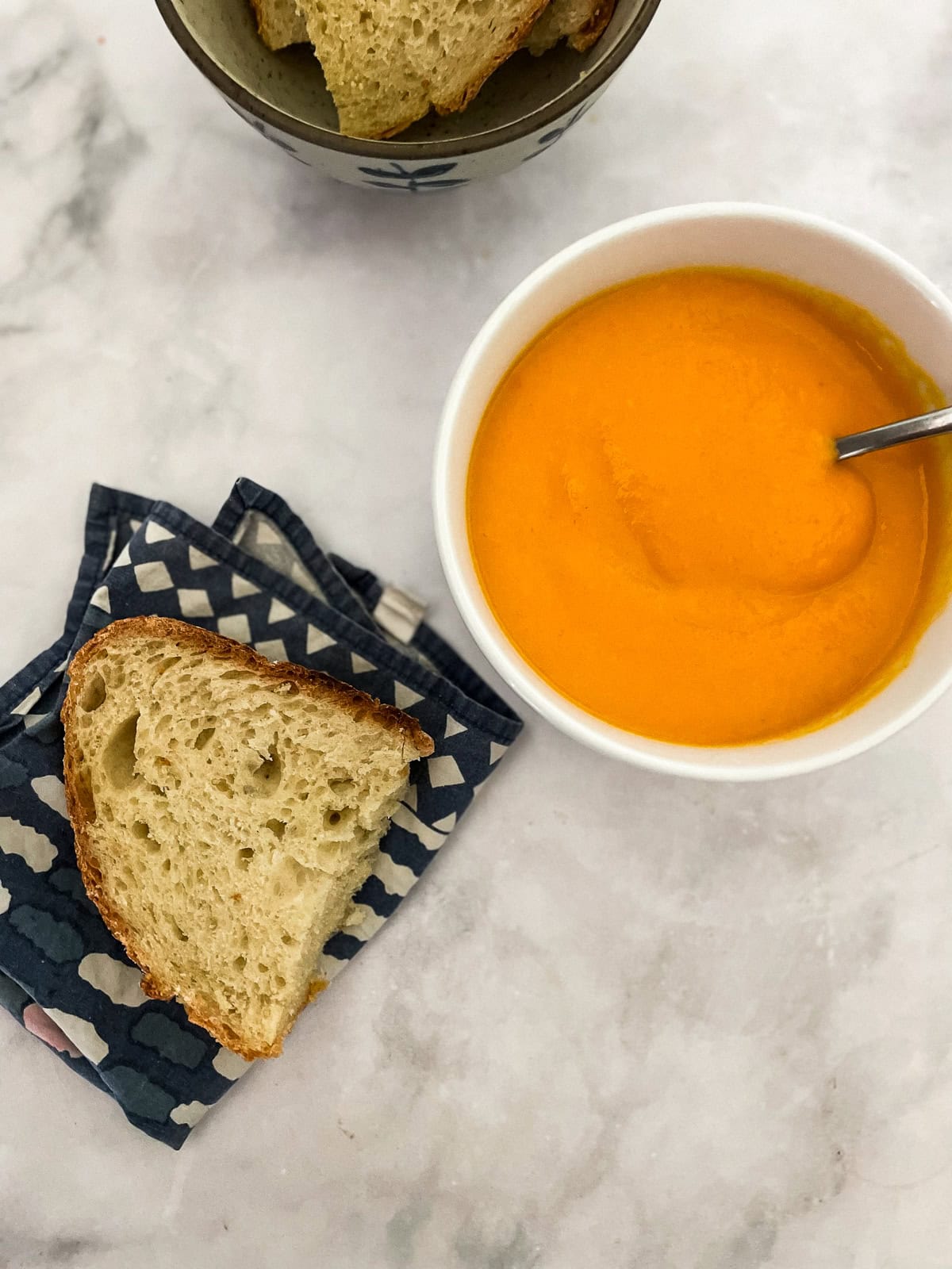 Creamy carrot & coconut soup made with simple ingredients. Naturally vegan, gluten-free, and perfect for weeknight dinners or meal prep. Slices of bread next to a bowl of carrot and coconut soup.