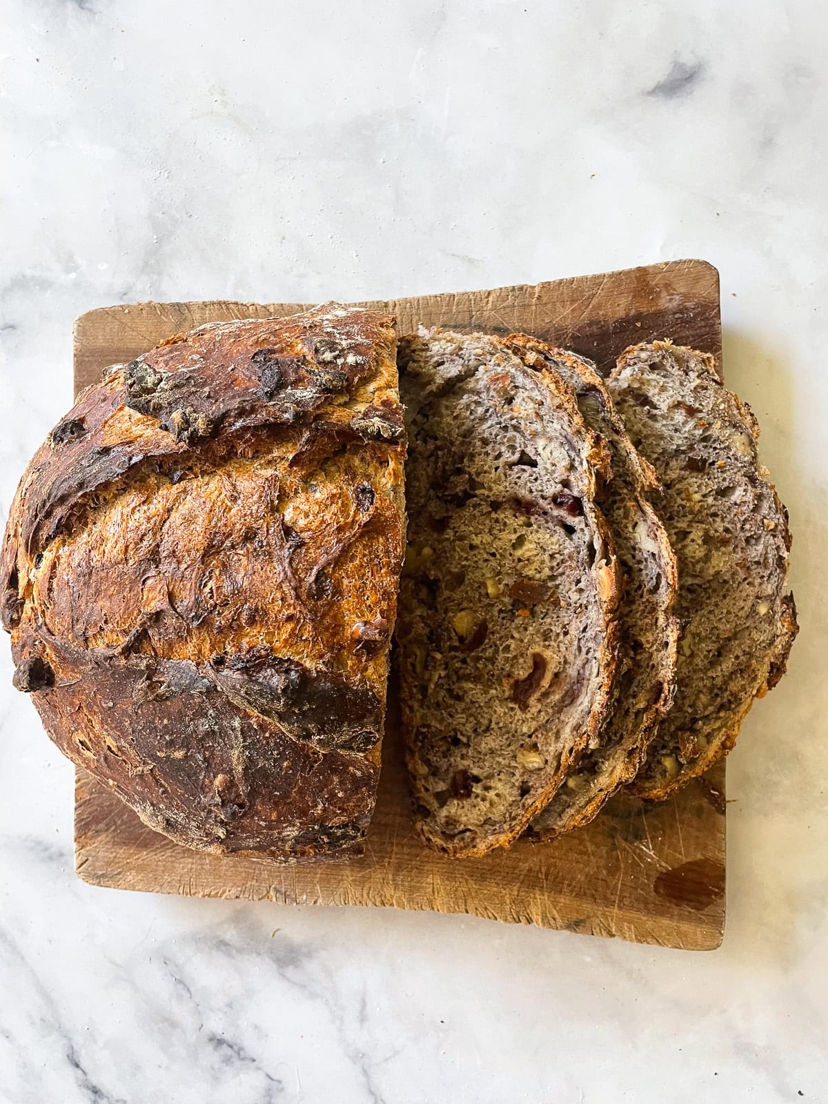 No-knead cranberry walnut bread is studded with sweet-tart dried fruit and crunchy nuts. An easy homemade version of a bakery loaf. Slices of cranberry walnut bread cut from a loaf.