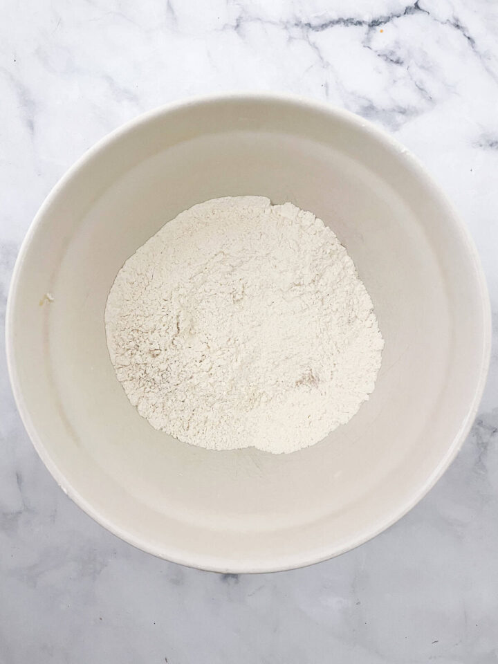 Kids love bunny bread that stars an easy, yeast-based dough that's simple to mix, fun to knead, and bakes up into the cutest golden bunnies. Yeast, sugar, salt, and flour mixed in a bowll.