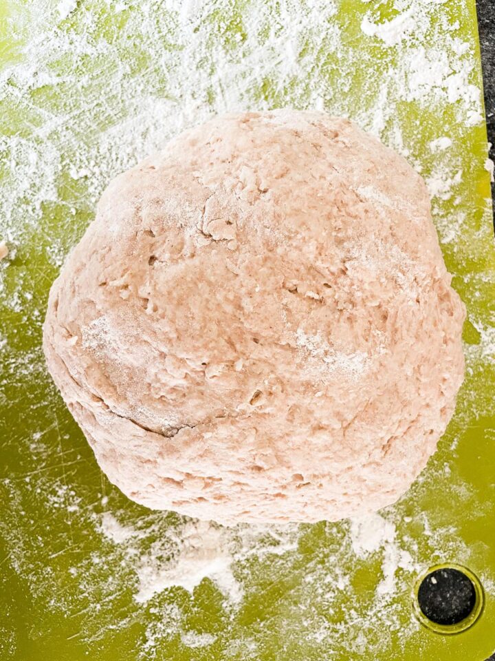 This porridge bread recipe turns leftover oatmeal into a beautifully soft and wholesome loaf! A great way to make sure nothing goes to waste. A ball of bread dough on a cutting board.