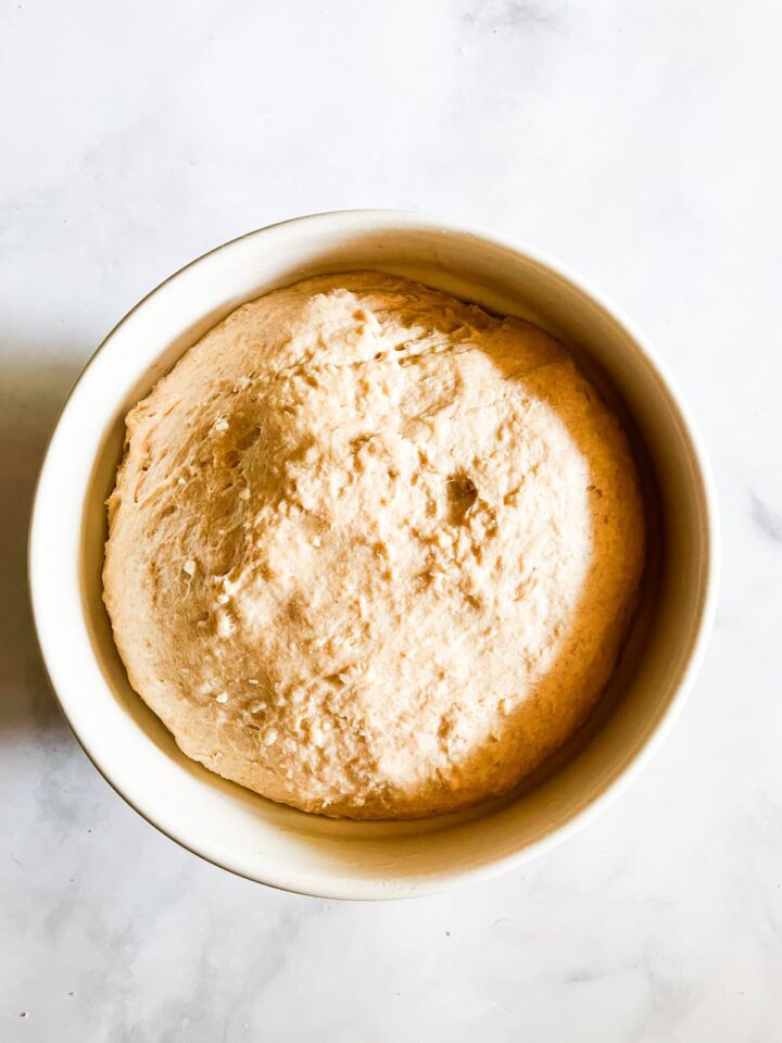 This porridge bread recipe turns leftover oatmeal into a beautifully soft and wholesome loaf! A great way to make sure nothing goes to waste. Bread dough after its final rise in a bowl.