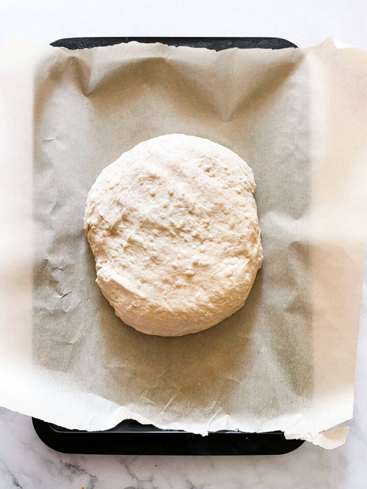 This porridge bread recipe turns leftover oatmeal into a beautifully soft and wholesome loaf! A great way to make sure nothing goes to waste. A loaf of bread dough on a parchment lined baking sheet.