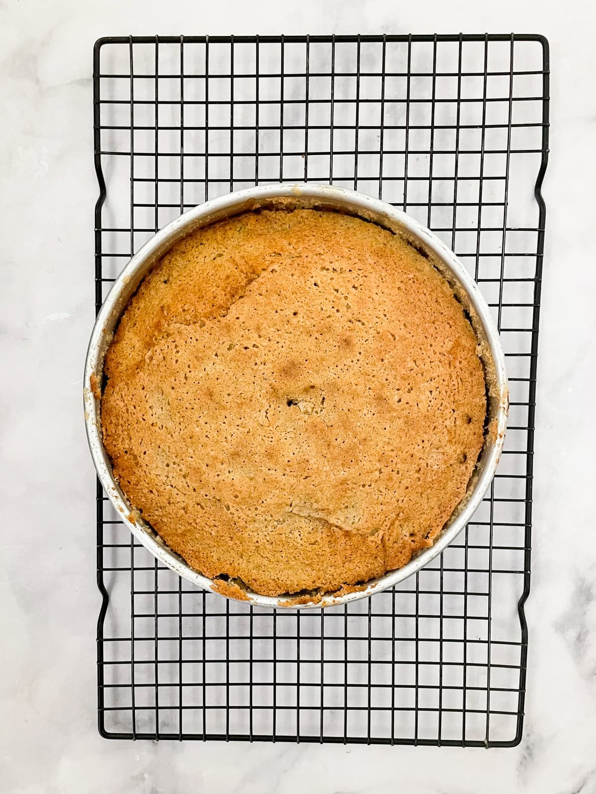 This gorgeous upside-down rhubarb cake drapes buttery rhubarb over a vanilla-scented cake for a beautiful, summery treat. An upside-down rhubarb cake cools on a rack.