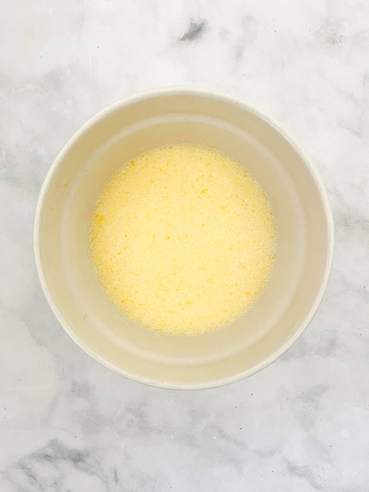 A cinnamon-kissed coconut loaf cake packed with bits of flaked coconut. Inspired by the classic Bill Granger recipe from "Australian Food." Eggs mixed with milk and butter in a bowl.