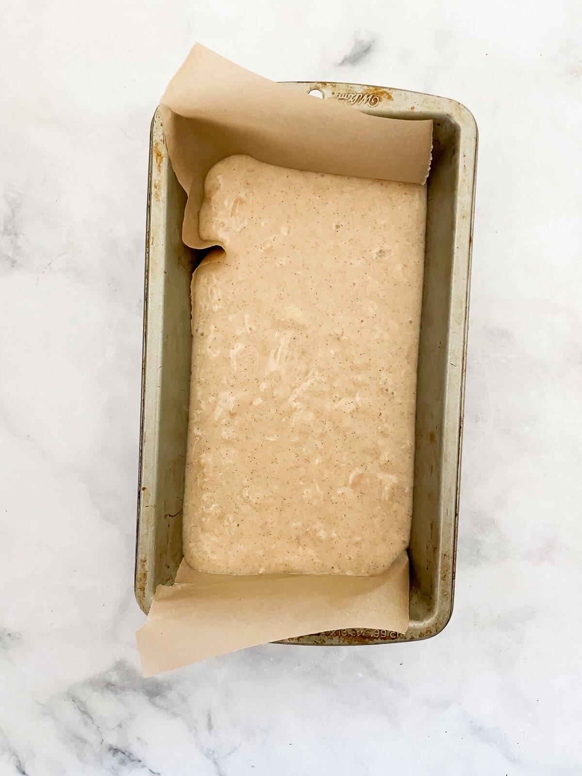 A cinnamon-kissed coconut loaf cake packed with bits of flaked coconut. Inspired by the classic Bill Granger recipe from "Australian Food." Coconut loaf cake batter in a lined loaf pan.
