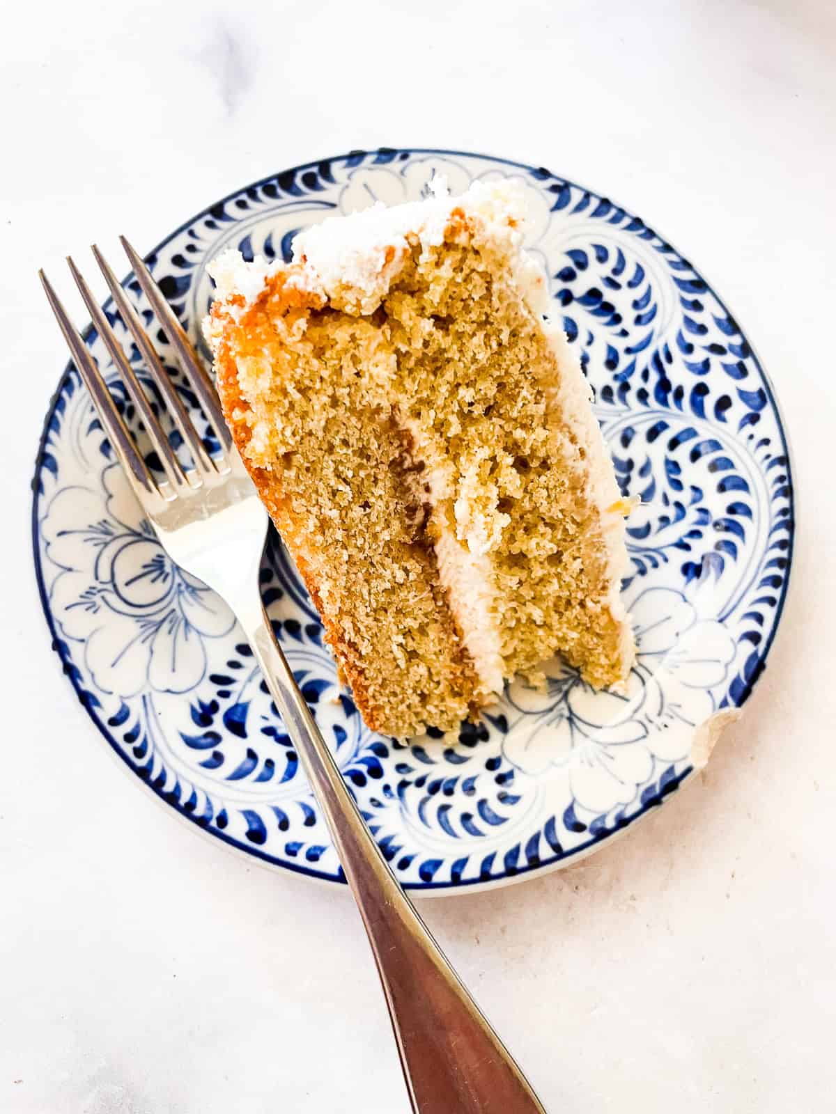 A fork rests on a plate next to a slice of rhubarb cake with whipped cream.