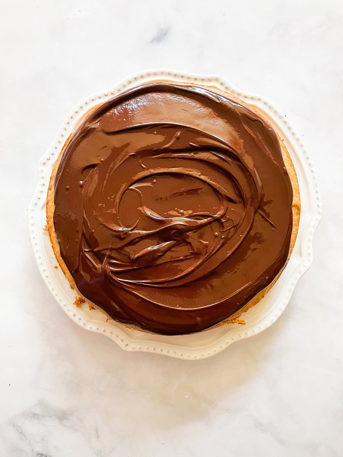 A lusciously moist, spice-kissed banana cake with chocolate frosting is the simplest recipe that always manages to impress! A banana cake with chocolate frosting on a plate.