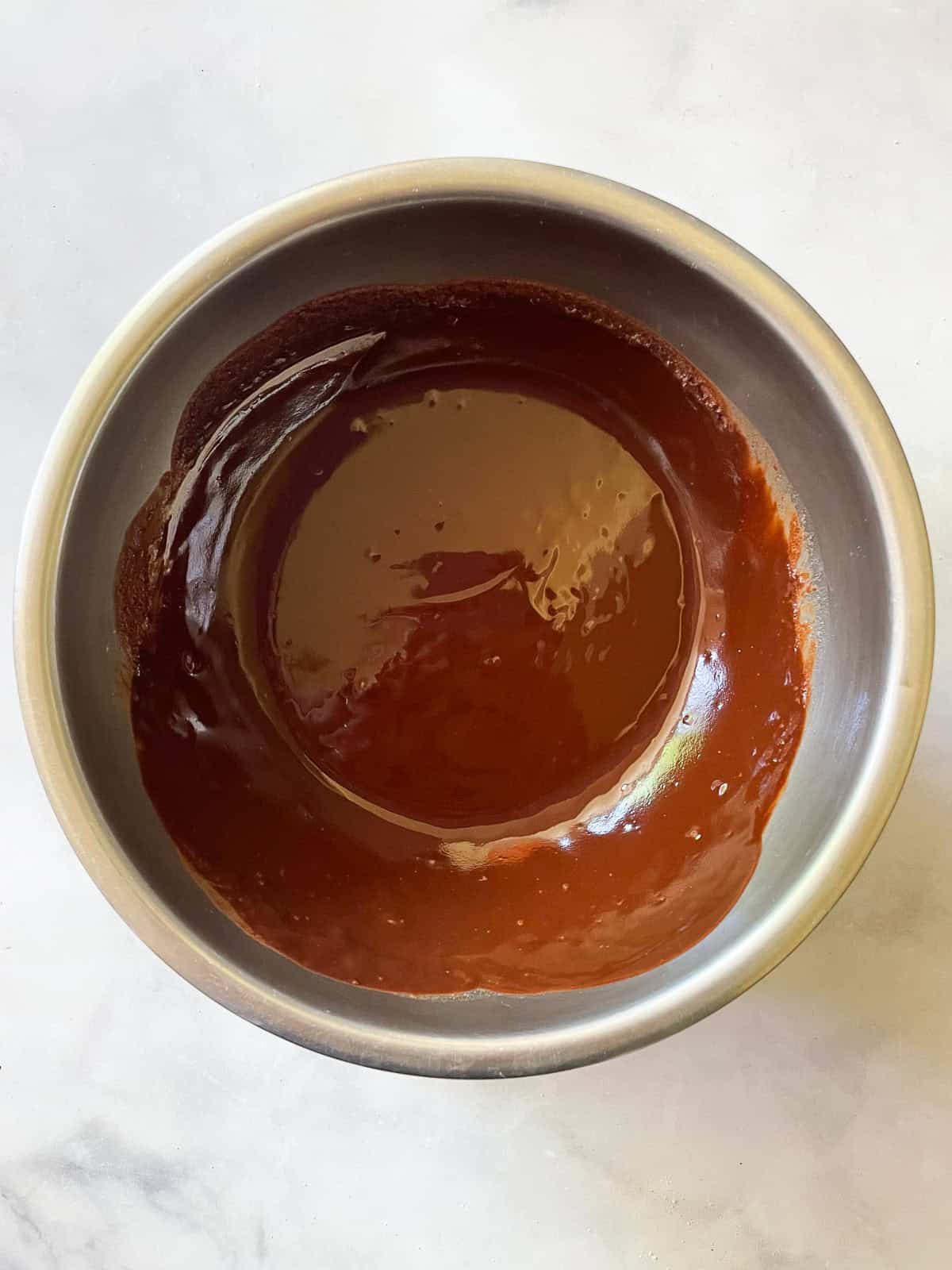 Melted chocolate frosting in a bowl.